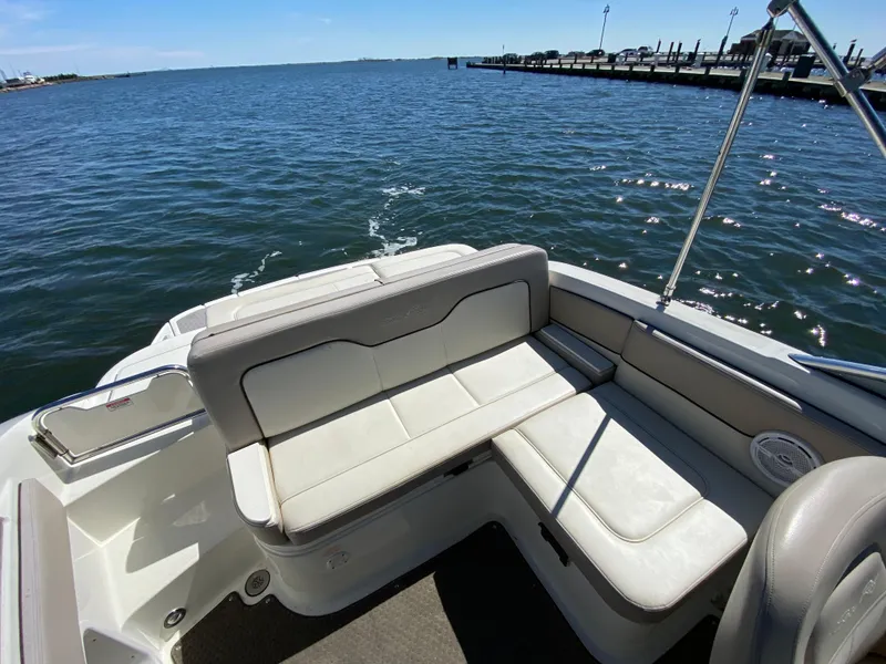 Slide: The Image of 2011 Sea Ray 240 Sundeck boat interior with white seating, on calm water near a dock. - 13