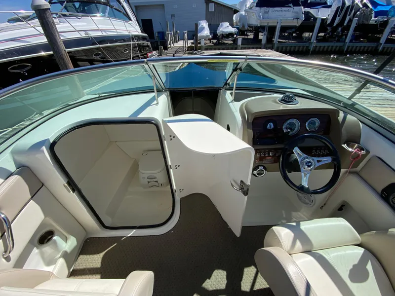 Slide: The Image of 2011 Sea Ray 240 Sundeck boat interior with open cabin door and steering console. - 16