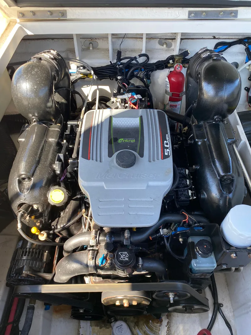 Slide: The Image of 2011 Sea Ray 240 Sundeck engine compartment with 5.0L engine and fire extinguisher. - 23