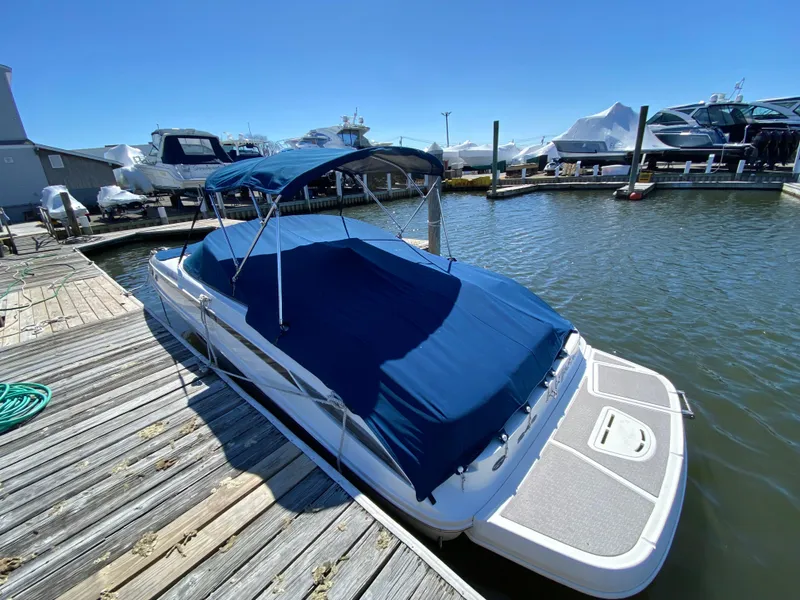 Slide: The Image of 2011 Sea Ray 240 Sundeck boat docked with blue cover and canopy. - 24
