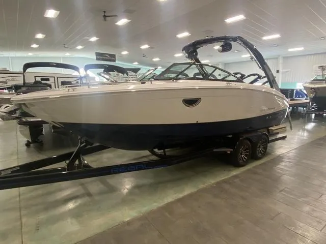Slide: The Image of 2024 Regal LS6 boat on display in showroom, sleek design, white and blue exterior. - 4