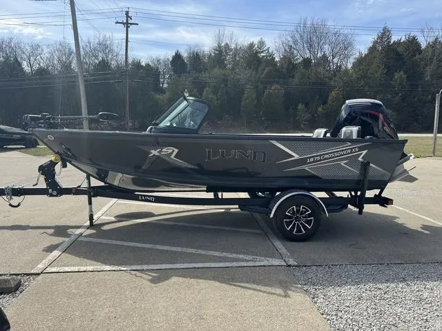 Slide: The Image of 2024 Lund 1875 Crossover XS Sport boat on a trailer in a parking lot. - 9