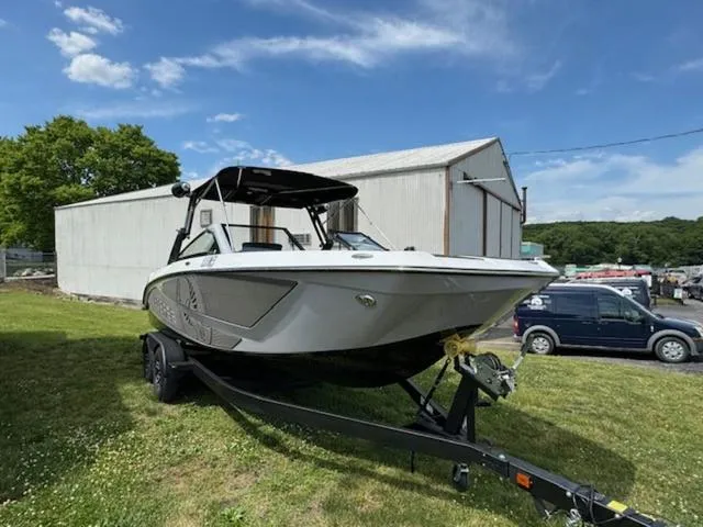Slide: The Image of 2025 Scarab 235 Wake boat on a trailer in a grassy area. - 2