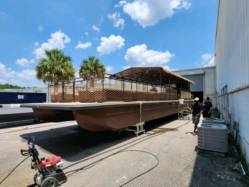Slide: The Image of A&M Manufacturing BullDog 50 pontoon boat, 2024 model, under construction outdoors. - 17