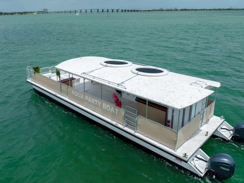 Slide: The Image of 2024 A&M Manufacturing BullDog 50 Aqua Party Boat cruising on a scenic waterway. - 2