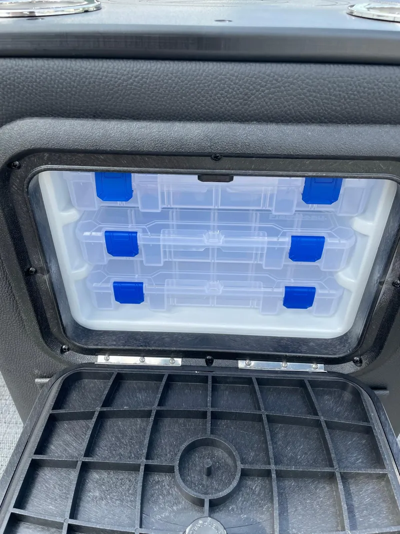 Slide: The Image of Storage compartment in the 2024 Barletta Aria 22CC boat with organized plastic containers. - 14