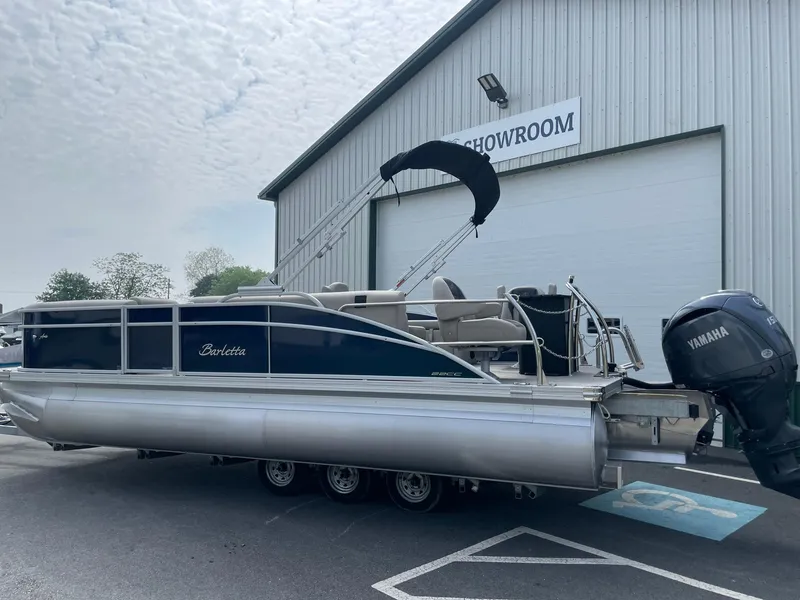 Slide: The Image of 2024 Barletta Aria 22CC pontoon boat outside showroom with Yamaha outboard motor. - 2