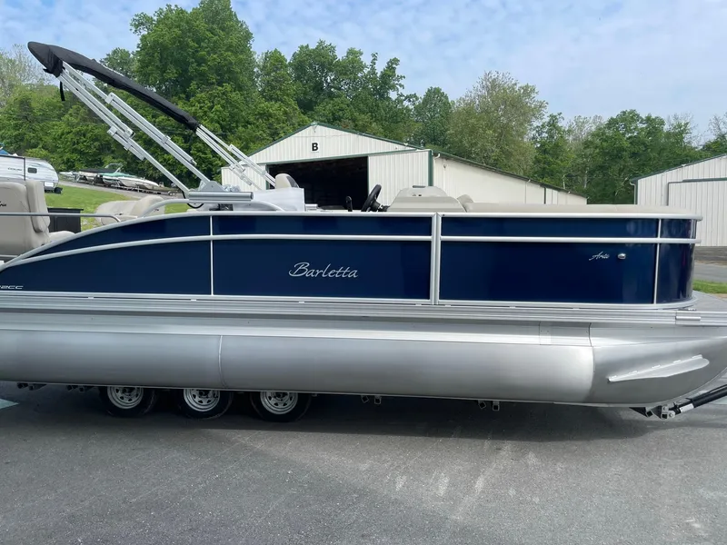 Slide: The Image of 2024 Barletta Aria 22CC pontoon boat with blue exterior, parked on pavement. - 5