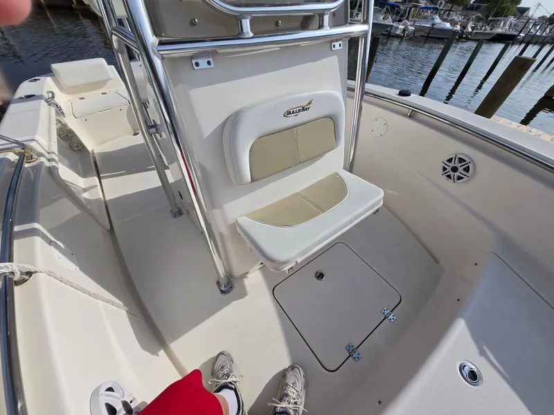 Slide: The Image of 2021 Bulls Bay 200 CC boat interior with seating and storage, docked by the water. - 26