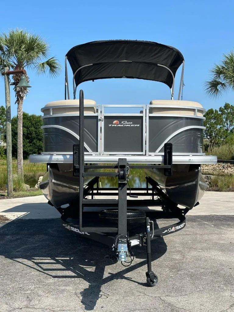 Slide: The Image of 2024 Sun Tracker Party Barge 24 DLX pontoon boat on a trailer, front view. - 2