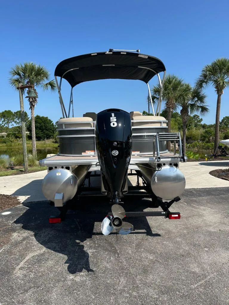 Slide: The Image of 2024 Sun Tracker Party Barge 24 DLX pontoon boat with outboard motor, parked on a sunny day. - 3