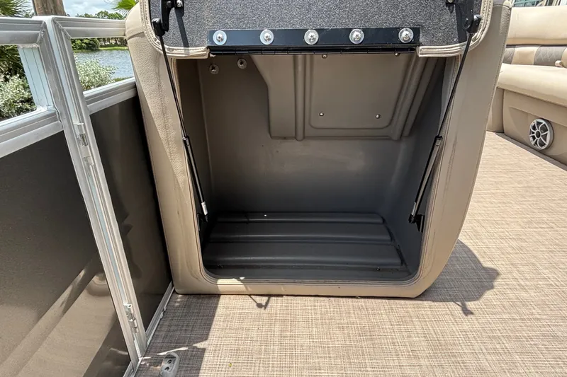 Slide: The Image of 2024 Sun Tracker Party Barge 24 DLX storage compartment, open on deck, beige interior. - 16