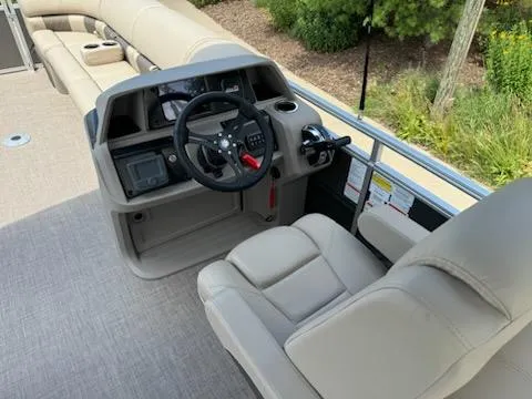 Slide: The Image of 2024 Sun Tracker Party Barge 24 DLX helm station with beige seating and control panel. - 2