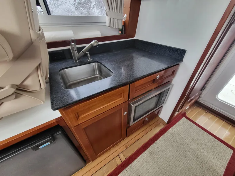 Slide: The Image of Compact kitchen area in a 2012 Crusader Boats outboard cruiser with sink and wooden cabinetry. - 11