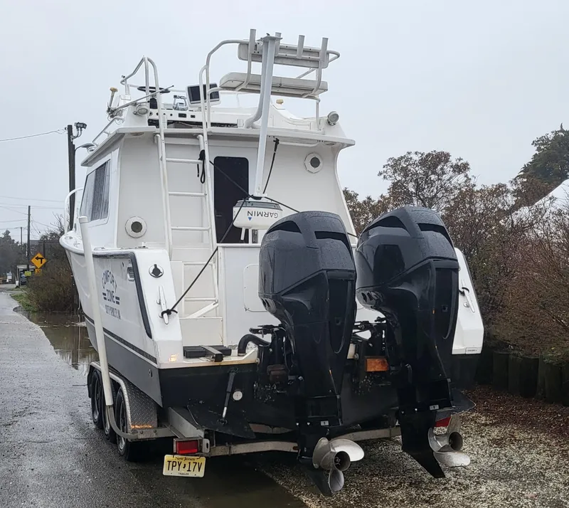 Slide: The Image of 2012 Crusader Boats outboard cruiser on trailer, featuring dual engines, parked on a wet road. - 14