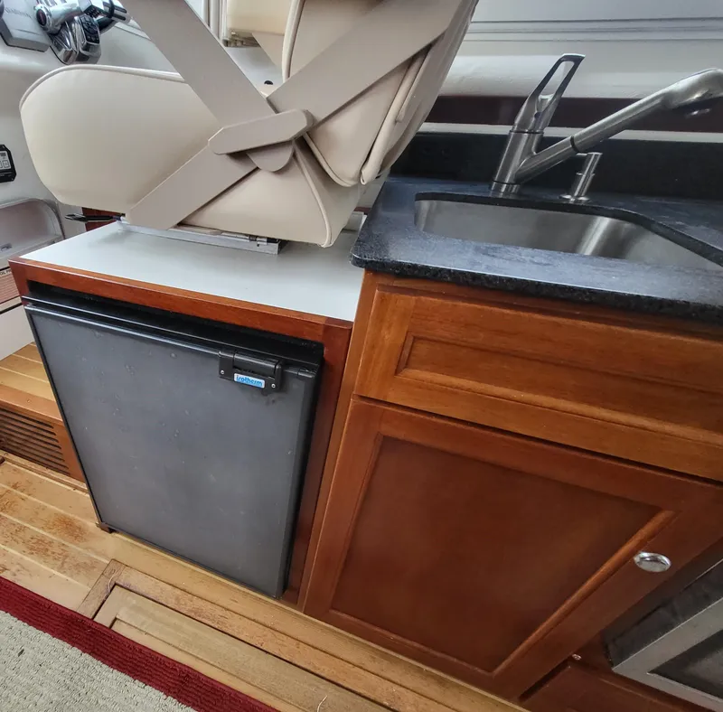 Slide: The Image of Interior of 2012 Crusader Boats outboard cruiser with seat, fridge, and sink. - 17