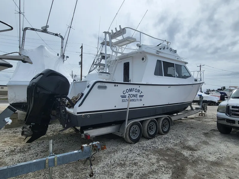 Slide: The Image of 2012 Crusader Boats outboard cruiser on trailer, named "Comfort Zone," parked outdoors. - 27