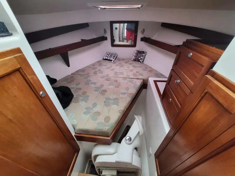 Slide: The Image of 2012 Crusader Boats outboard cruiser cabin with bed, wooden cabinets, and floral bedding. - 4