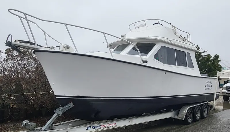 Slide: The Image of 2012 Crusader Boats outboard cruiser on a trailer, white hull, parked outdoors. - 7