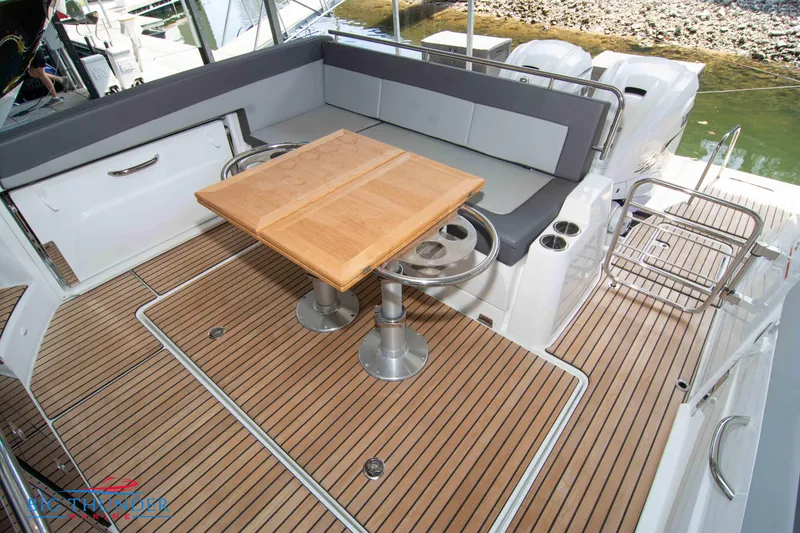 Slide: The Image of 2024 Jeanneau Leader 10.5 WA boat deck with seating and wooden table. - 16