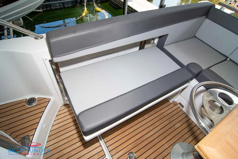 Slide: The Image of 2024 Jeanneau Leader 10.5 WA boat interior with gray seating and wooden deck. - 19