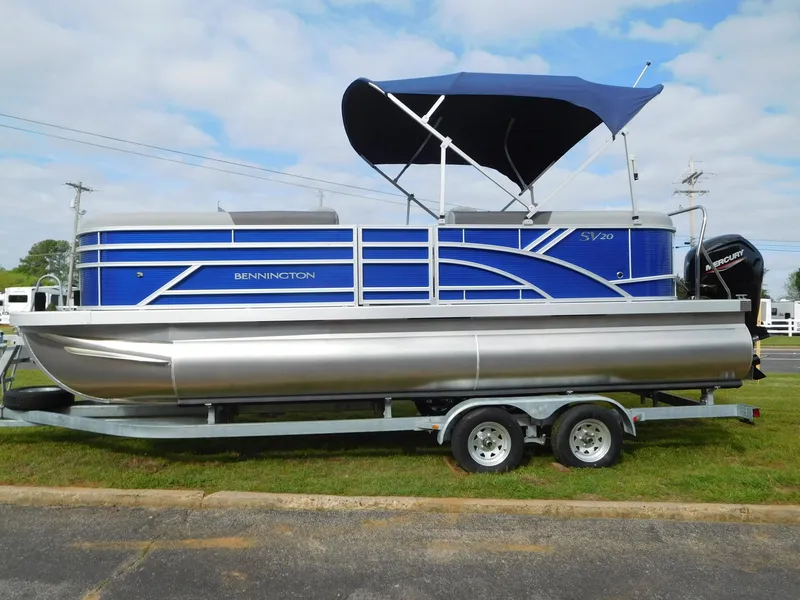 Slide: The Image of 2024 Bennington 20 SVSR pontoon boat with blue canopy on trailer. - 1