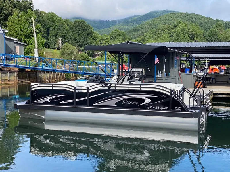 Slide: The Image of 2024 JC Neptoon Sport 23TT DSL pontoon boat docked on a serene lake. - 4