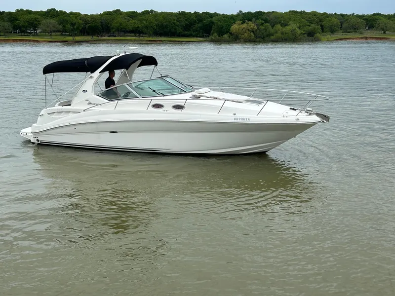 Slide: The Image of 2007 Sea Ray 320 Sundancer boat on calm water with lush green shoreline. - 30