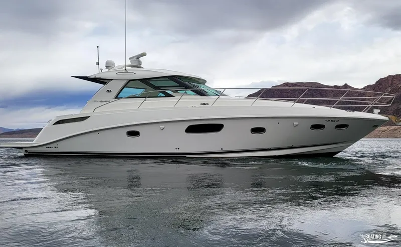Slide: The Image of 2012 Sea Ray 450 Sundancer yacht cruising on a lake with mountainous background. - 2