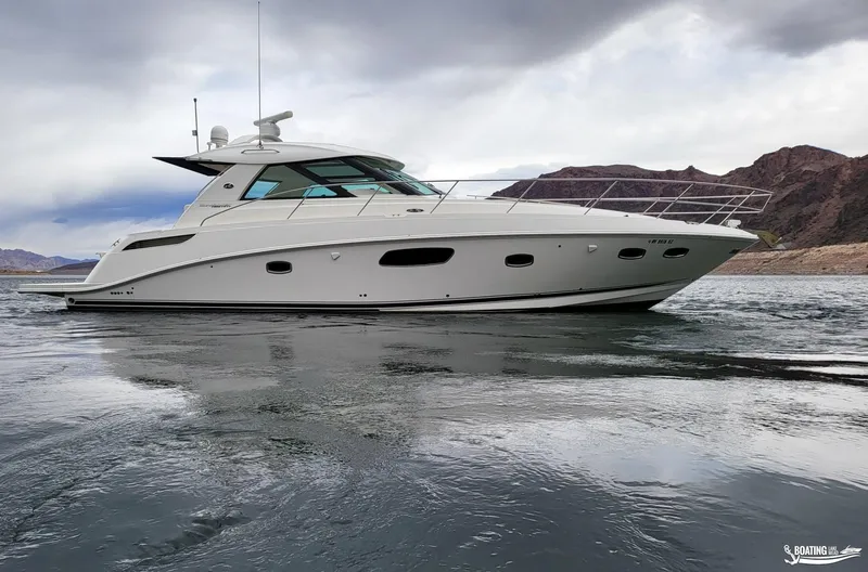 Slide: The Image of 2012 Sea Ray 450 Sundancer yacht cruising on a lake with mountainous background. - 6