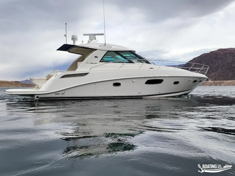 Slide: The Image of 2012 Sea Ray 450 Sundancer yacht on calm water with mountainous background. - 8