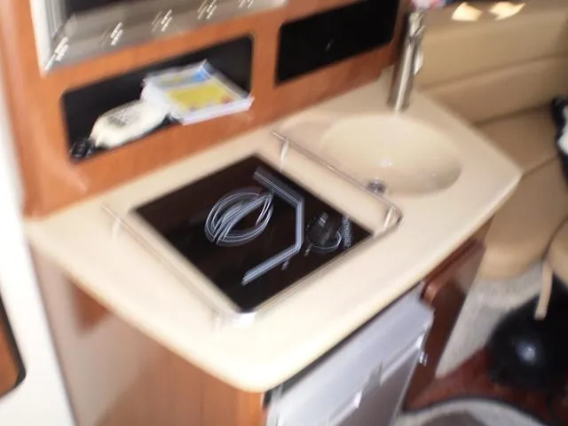 Slide: The Image of 2021 Crownline 264 CR boat interior kitchen with stove, sink, and storage. - 11