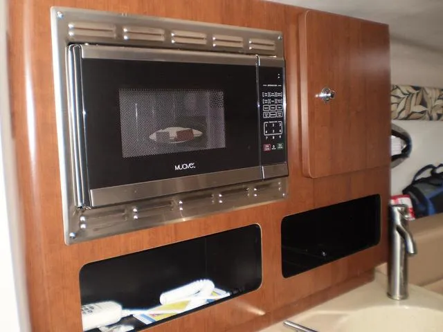 Slide: The Image of Microwave and storage cabinets in the 2021 Crownline 264 CR boat kitchen. - 13