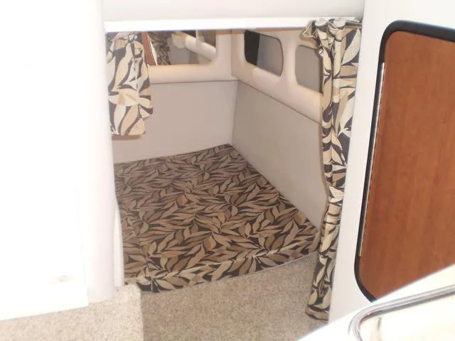 Slide: The Image of 2021 Crownline 264 CR cabin interior with patterned bedding and curtains. - 35