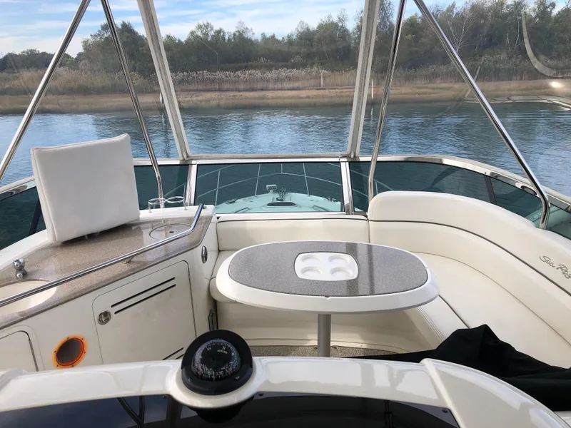 Slide: The Image of 2006 Sea Ray 52 Sedan Bridge yacht interior with seating and table on calm water. - 10