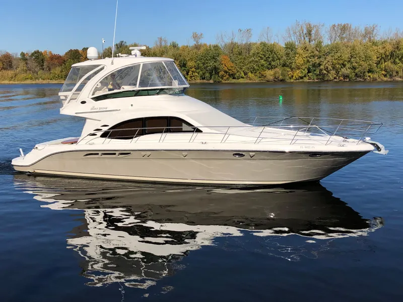Slide: The Image of 2006 Sea Ray 52 Sedan Bridge yacht on calm water with trees in the background. - 2