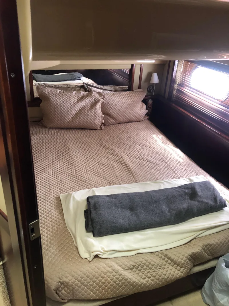 Slide: The Image of 2006 Sea Ray 52 Sedan Bridge bedroom with cozy bedding and window view. - 31