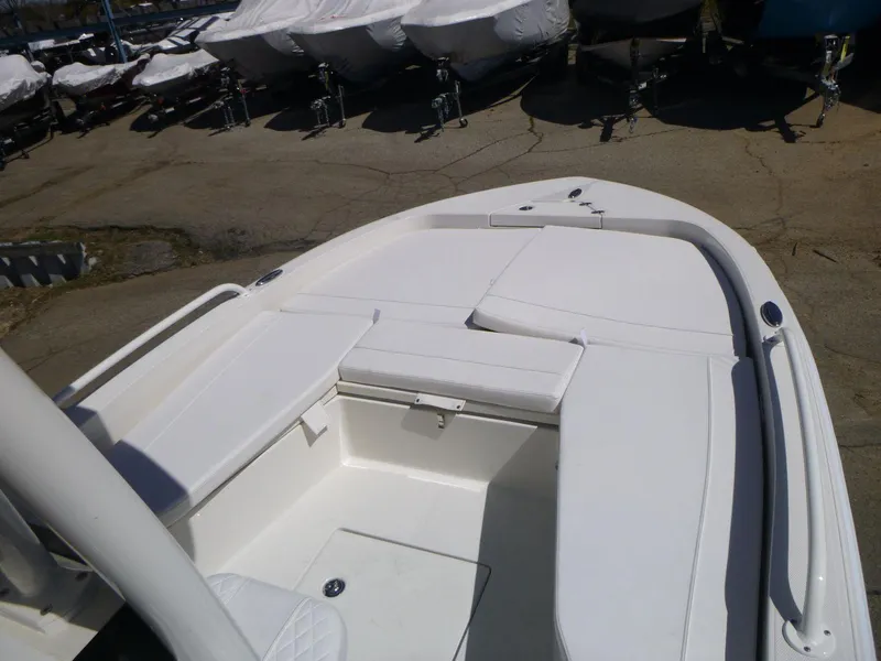 Slide: The Image of 2024 Ranger 2360 Bay boat, white deck, docked with covered boats in background. - 10