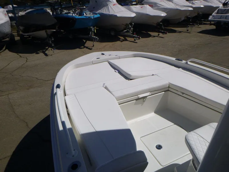 Slide: The Image of 2024 Ranger 2360 Bay boat interior with white seating, parked among covered boats. - 8