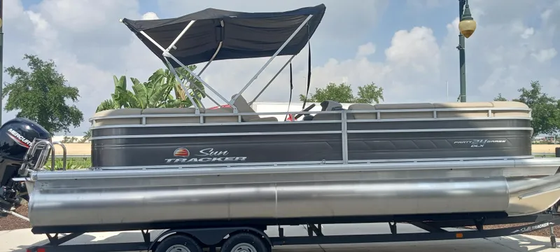 The Image of 2024 Sun Tracker Party Barge 24 DLX pontoon boat with canopy on trailer. - 0