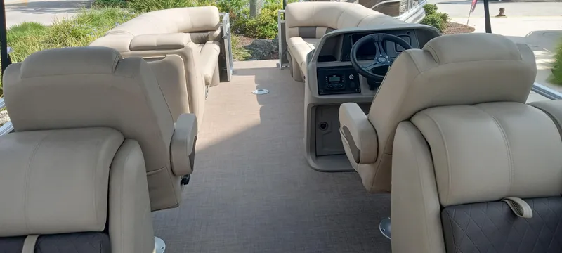 Slide: The Image of 2024 Sun Tracker Party Barge 24 DLX interior with beige seating and steering console. - 4