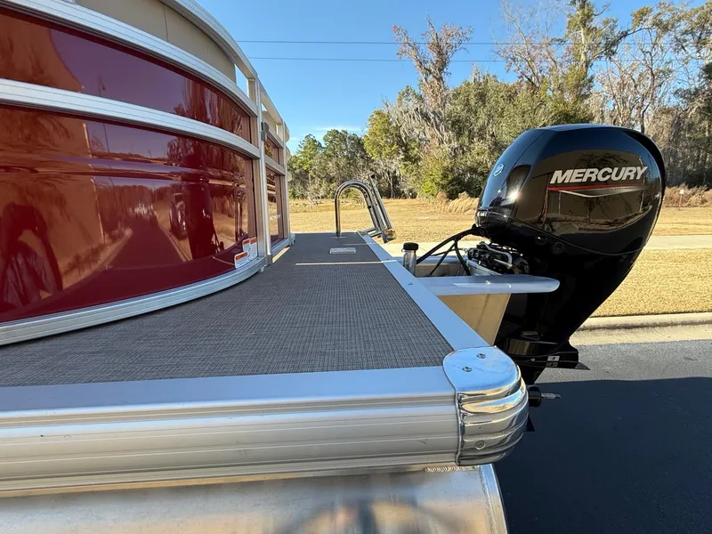 Slide: The Image of 2024 Sun Tracker Party Barge 24 DLX with Mercury outboard motor, red and silver design. - 2