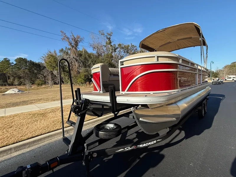 Slide: The Image of 2024 Sun Tracker Party Barge 24 DLX pontoon boat on trailer, parked on street. - 3