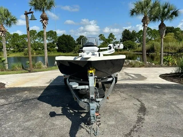 Slide: The Image of 2024 Ranger RB210 boat on trailer, parked near a scenic lake with palm trees. - 2