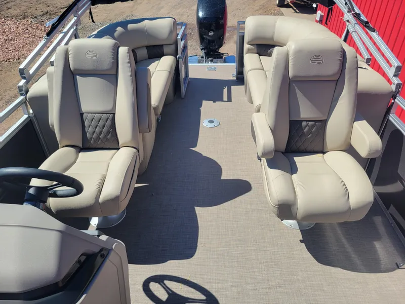 Slide: The Image of 2024 Sun Tracker Party Barge 24 DLX interior with beige seating and steering console. - 2