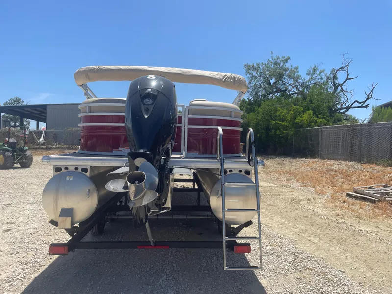 Slide: The Image of 2024 Sun Tracker Party Barge 24 DLX pontoon boat with outboard motor, parked outdoors. - 2