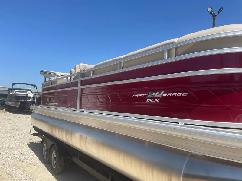 Slide: The Image of 2024 Sun Tracker Party Barge 24 DLX pontoon boat on trailer, sunny day. - 4