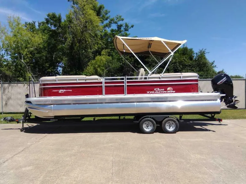 The Image of 2024 Sun Tracker Party Barge 24 DLX pontoon boat on a trailer, red and silver. - 0