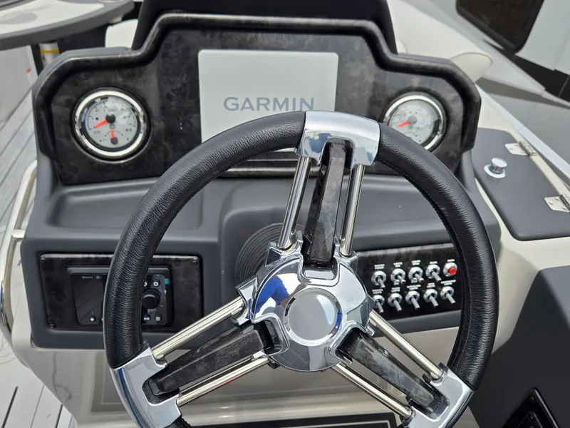 Slide: The Image of 2023 SunCatcher Elite 322 RC boat dashboard with Garmin display and steering wheel. - 6