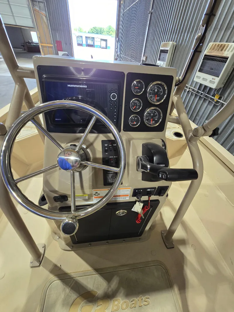 Slide: The Image of 2023 G3 Bay 20 GX boat console with steering wheel and gauges in a warehouse. - 11